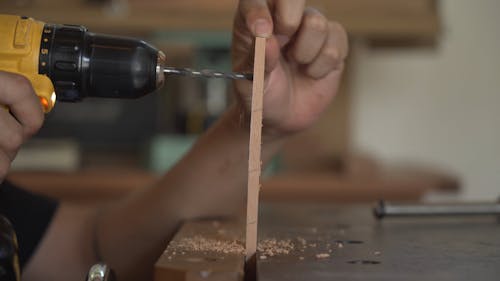 Male Hands Using Hand Drill on Wood Strip Close up
