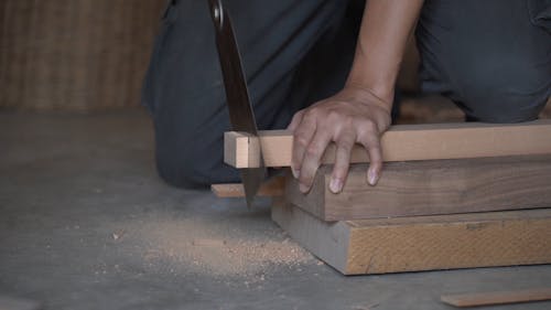 Male Hands Sawing Piece of Wood Close up