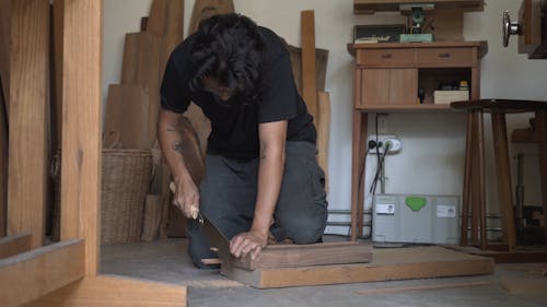 Young Man Cutting Wood Strip with Hand Saw