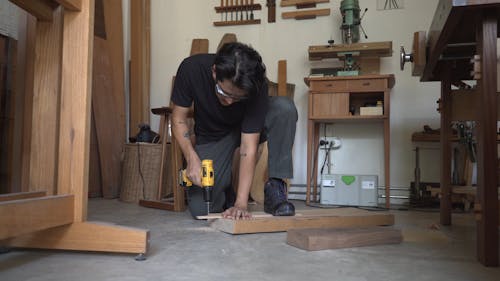 A Man Using a Hand Drill on Wood