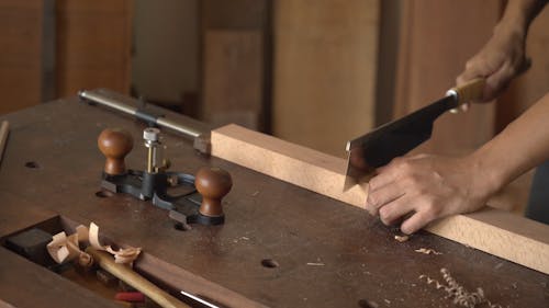 A Person Using a Hand Saw on Wood