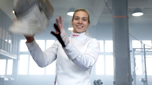 A Female Fencer Putting on a Mask and Holding a Sabre