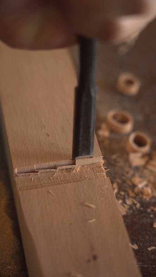 A Person Hammering a Chisel on Wood