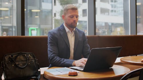 A Man Typing on His Laptop While in a Cafe