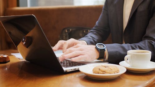 A Person Typing and Using His Laptop