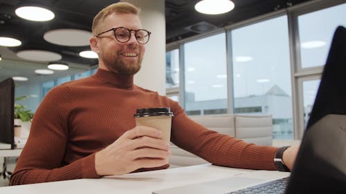 A Man Using A Laptop While Drinking Coffee