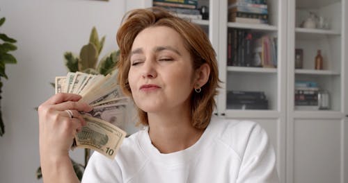 A Woman Fanning Herself With Money
