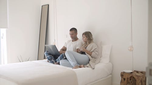 Мужчина и женщина сидят на кровати и разговаривают друг с другом