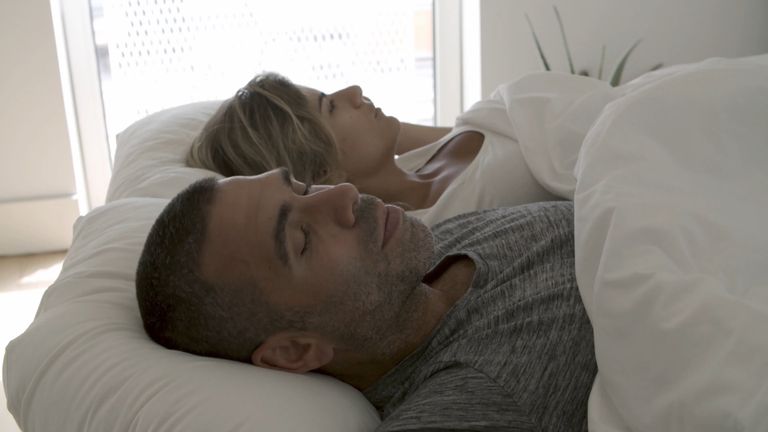 Two people asleep under a white blanket in a calm bedroom