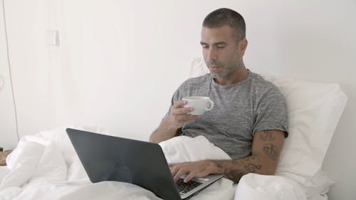 Man Drinking His Coffee While Using His Laptop