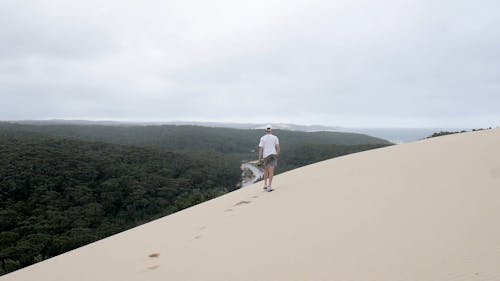 Back View of a Man Walking on Top of a Sand Dunes