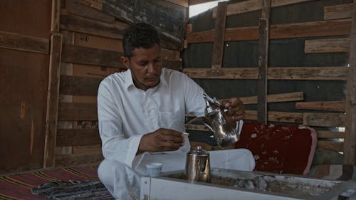 A Man Pouring Traditional Tea On A Glass Cup