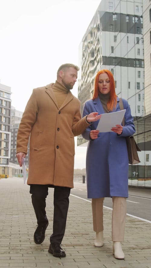 Man and Woman Walking Outdoors While Talking to Each Other