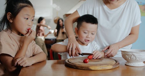 Mother Teaching Her Son to Cut a Strawberry