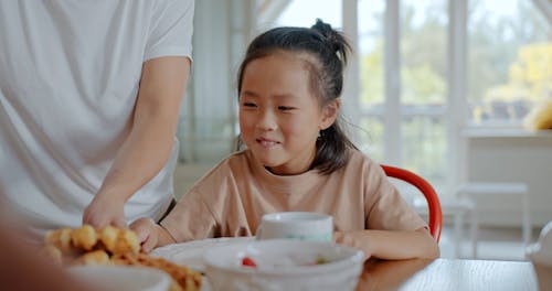 Person Giving Waffle to Girl's Plate