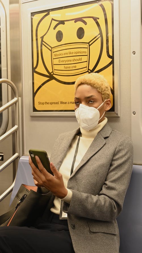 スマートフォンを使用しながら電車の中で座っている女性