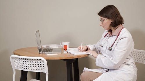 A Doctor Writing on a Notebook
