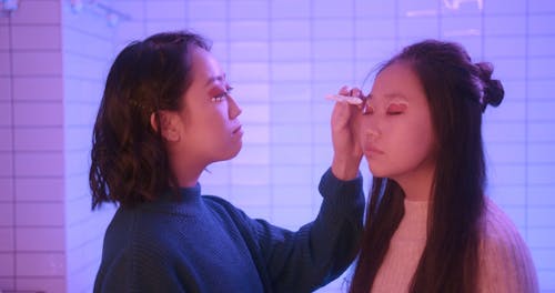 Woman Applying an Eyeshadow to Her Sister