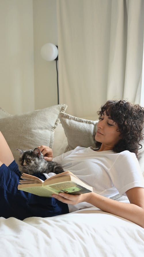 Женщина читает книгу со своим домашним котом
