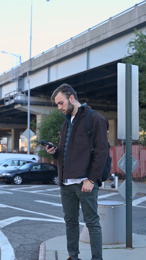 Man Standing Outdoors While Using His Smartphone