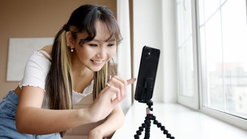 Woman Smiling While Browsing Her Smartphone