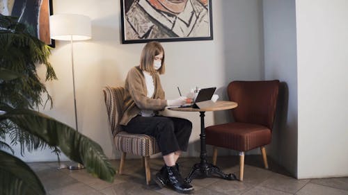 Woman Wearing Face Mask Writing on a Notebook