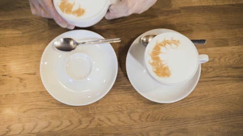 Person Putting a Cup of Coffee on a Saucer