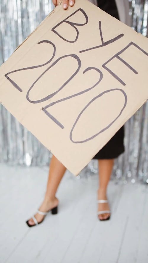 A Woman Holding A Sign Of Bye 2020