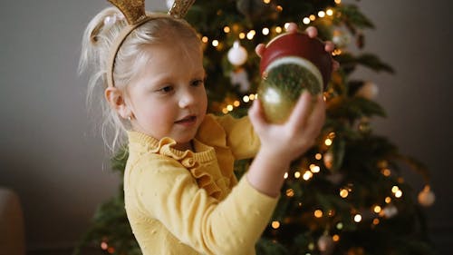 A Girl Shaking a Christmas Snow Globe