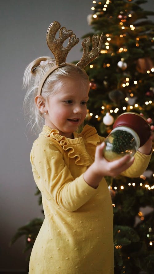 A Girl Shaking a Christmas Snow Globe