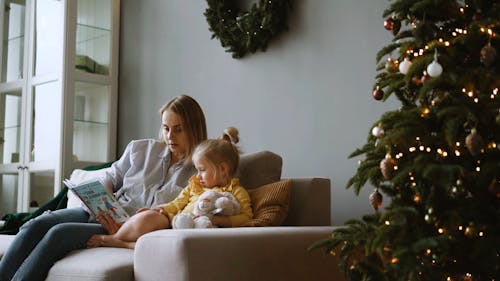 A Mother Reading a Story Book to Her Daughter