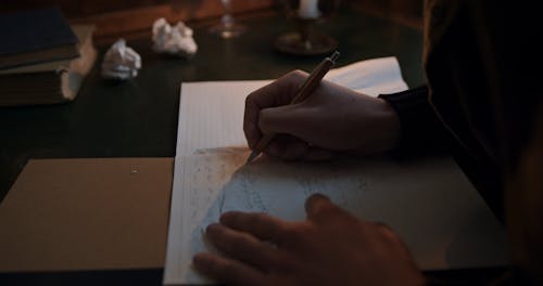 Close Up Shot of a Man Writing on the Notebook