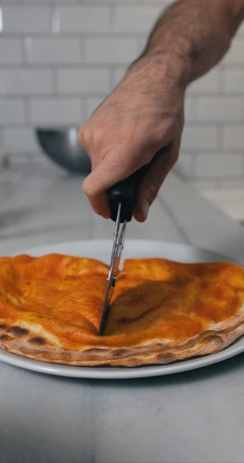 Person Slicing Half of a Pizza