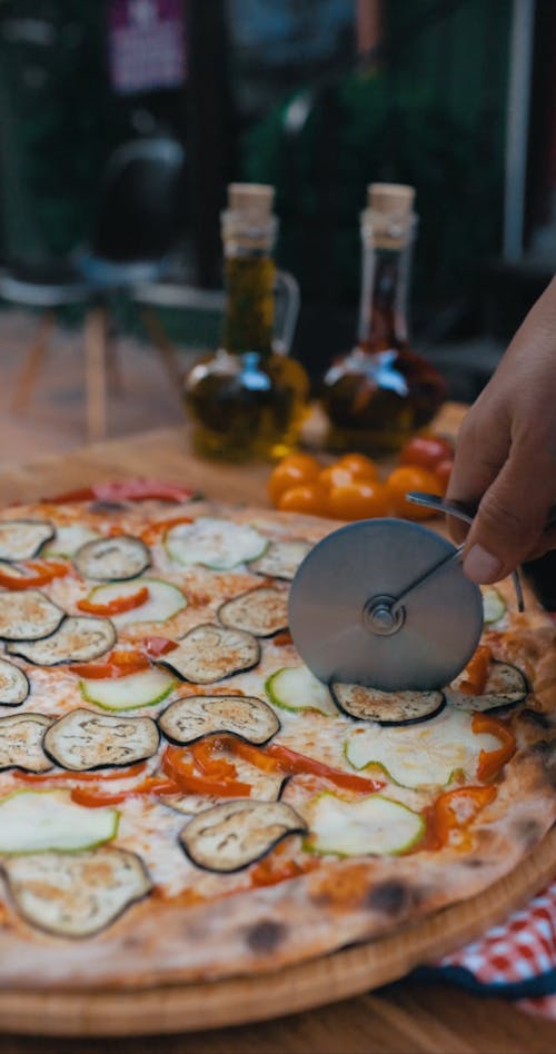 Person Slicing Pizza with a Pizza Cutter
