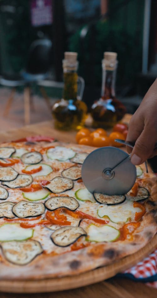 Person Slicing a Pizza with a Pizza Cutter