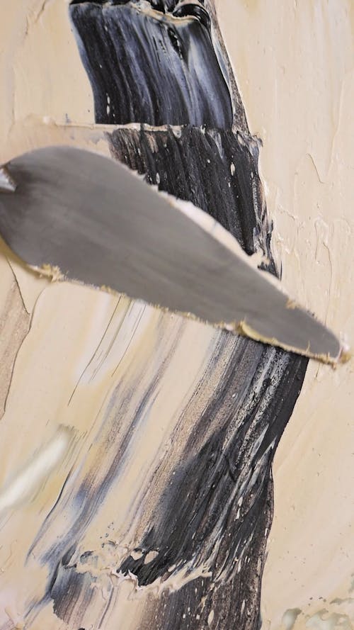 Person Using a Painting Knife to Spread Paint on a Canvas