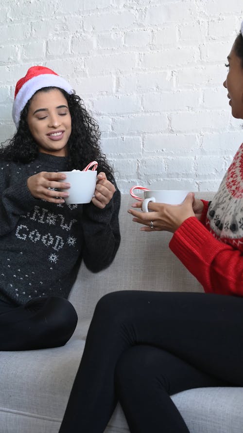 Women Holding Hot Beverages while Having a Conversation
