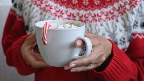 A Person Holding Hot Cocoa with a Candy Cane