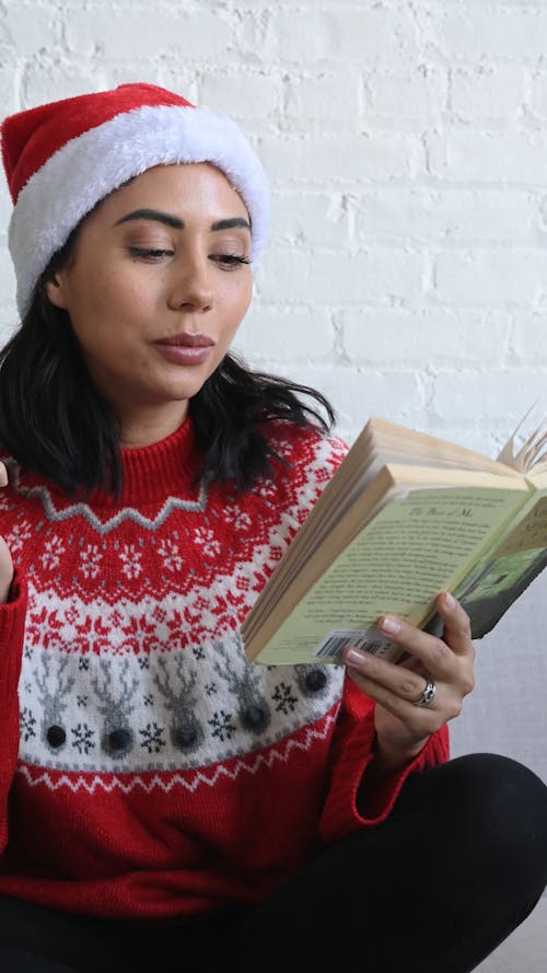 Woman Dressed In Christmas Costume While Reading and Eating a Cookie
