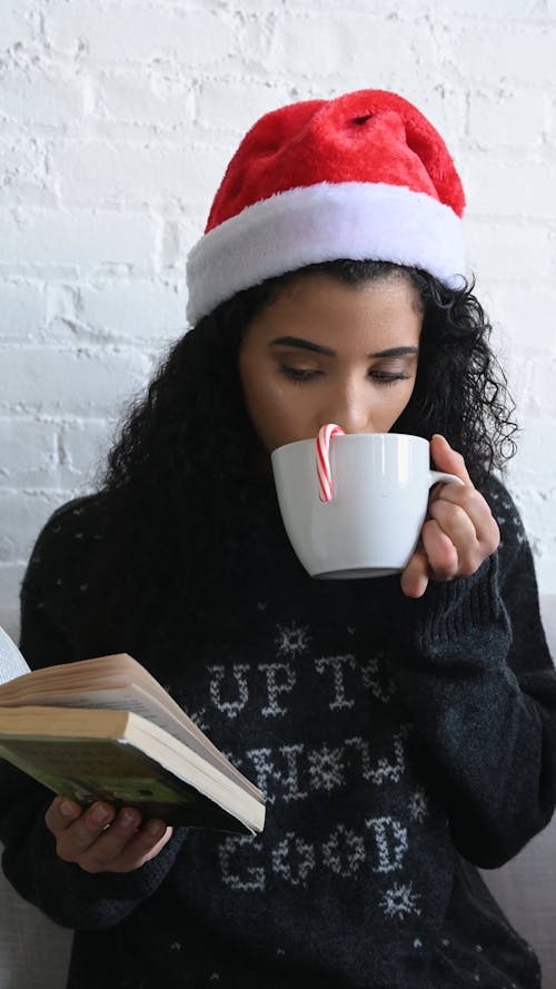 Woman Dressed In Christmas Costume While Reading and Holding a Mug