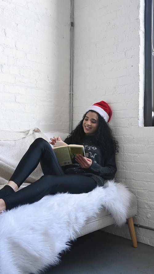 Person Wearing Christmas Hat Reading on the Couch