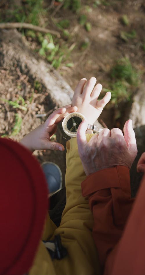 An Elderly Man Touching a Compass on his Grandchild's Wrist