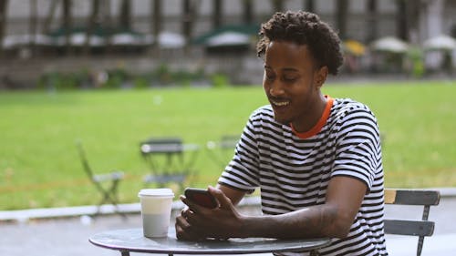 Man Drinking from a Cup While Using Cellphone