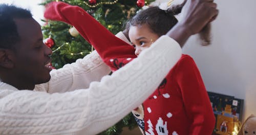 Dad Helping His Daughter Wear the Red Christmas Sweater