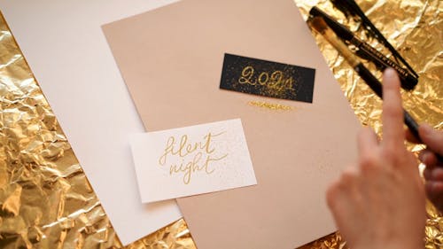 A Person Putting Gold Glitters on a Paper