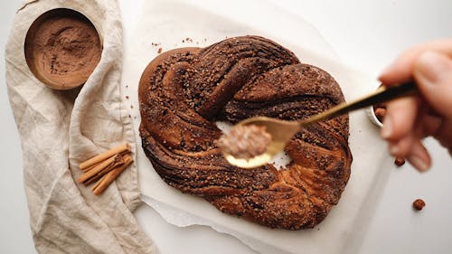 Woman Sprinkling Cocoa Powder on the Top of Babka Bread