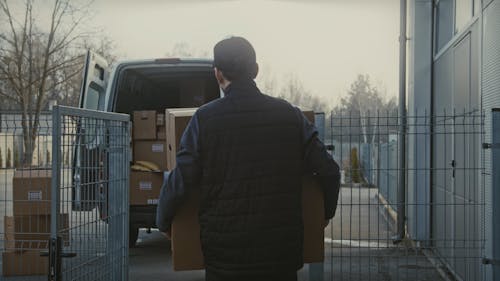 Delivery Man Loading Cardboard Boxes in Van