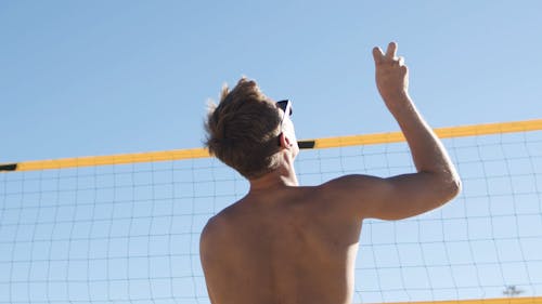 Back View of a Man Hitting a Ball Over the Net