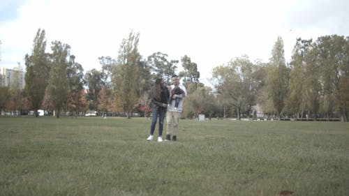 A Man and a Woman Walking in a Park with their Baby