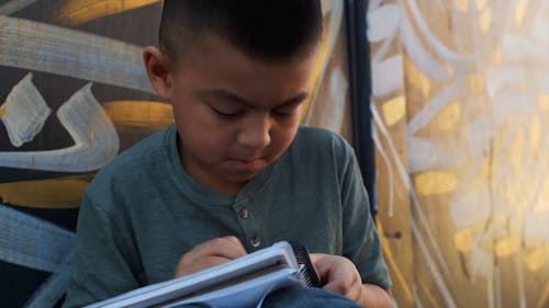 Little Boy Coloring on a Notepad